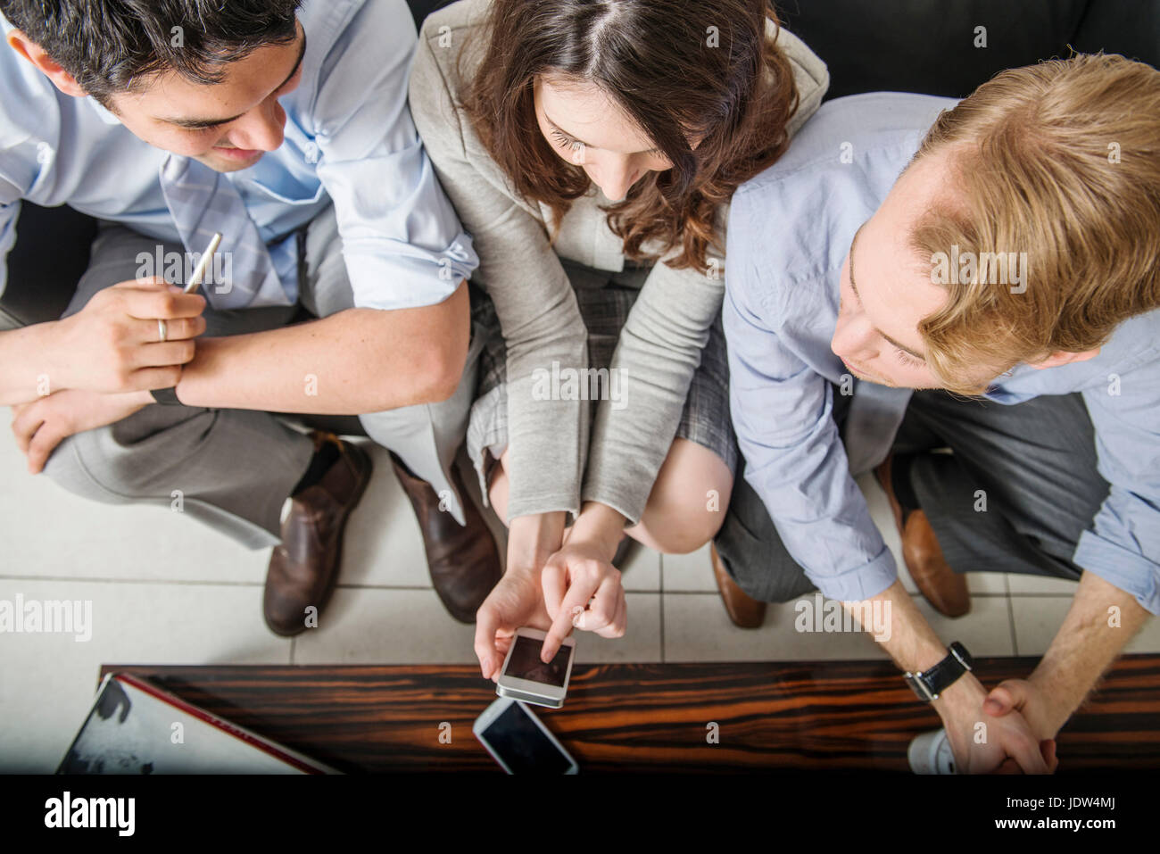 Office colleagues using cell phone, high angle Banque D'Images