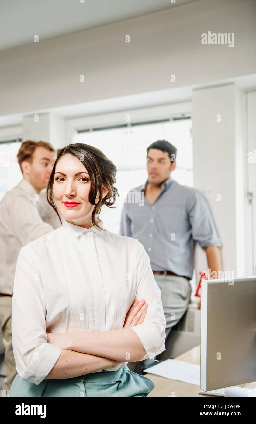 Portrait of female office worker, collègues masculins en arrière-plan Banque D'Images