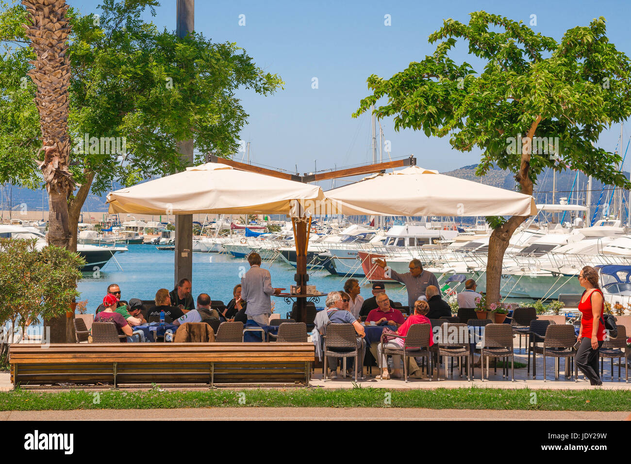 Les touristes de la Sardaigne, vous détendre au café des touristes pour le déjeuner sur la terrasse d'un café au bord de l'eau le long de la Via Garibaldi, dans le port d'Alghero, Sardaigne. Banque D'Images