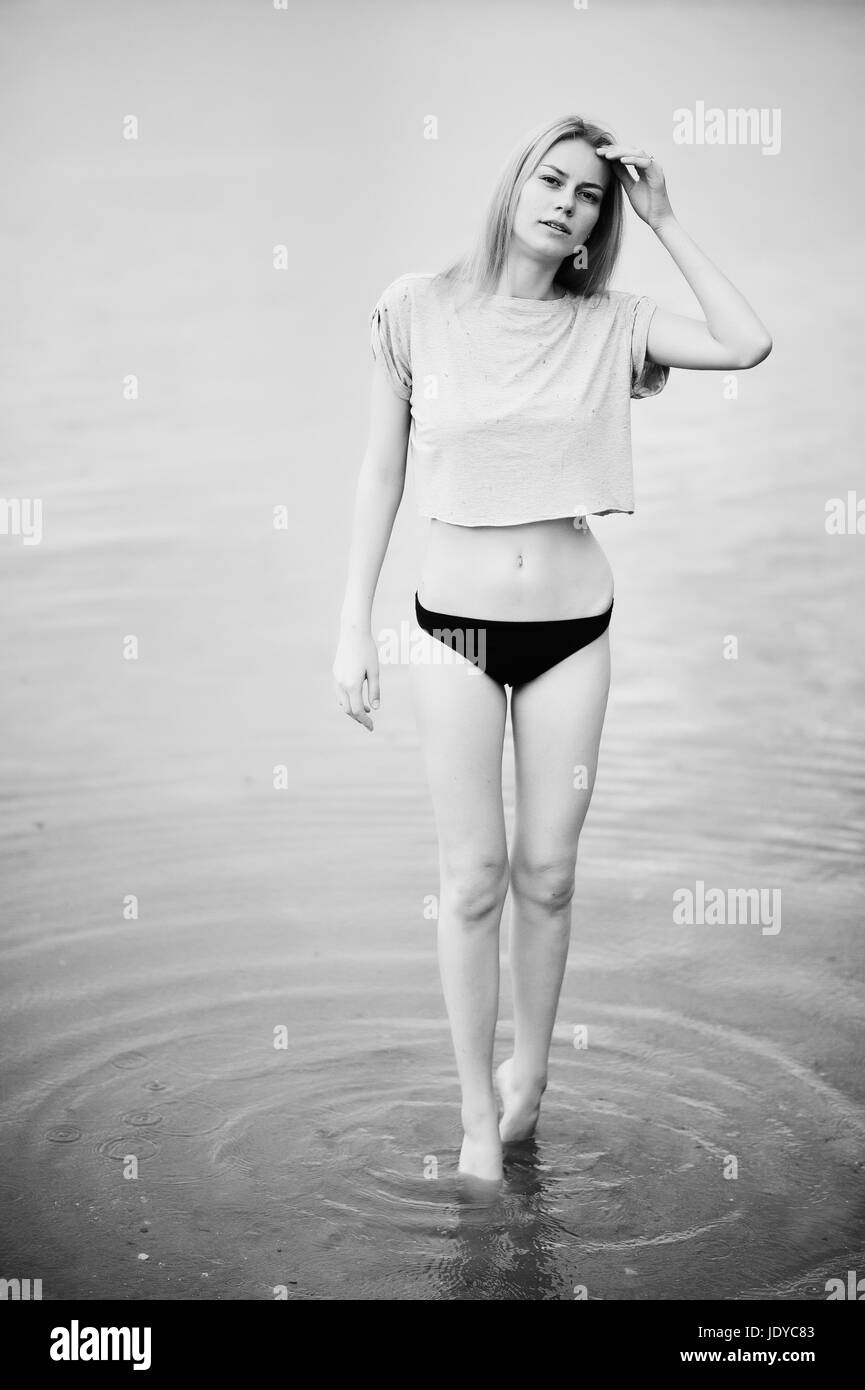 Portrait d'un modèle de grande taille à porter un t-shirt et d'un bikini dans le lac à pied. Photo en noir et blanc. Banque D'Images