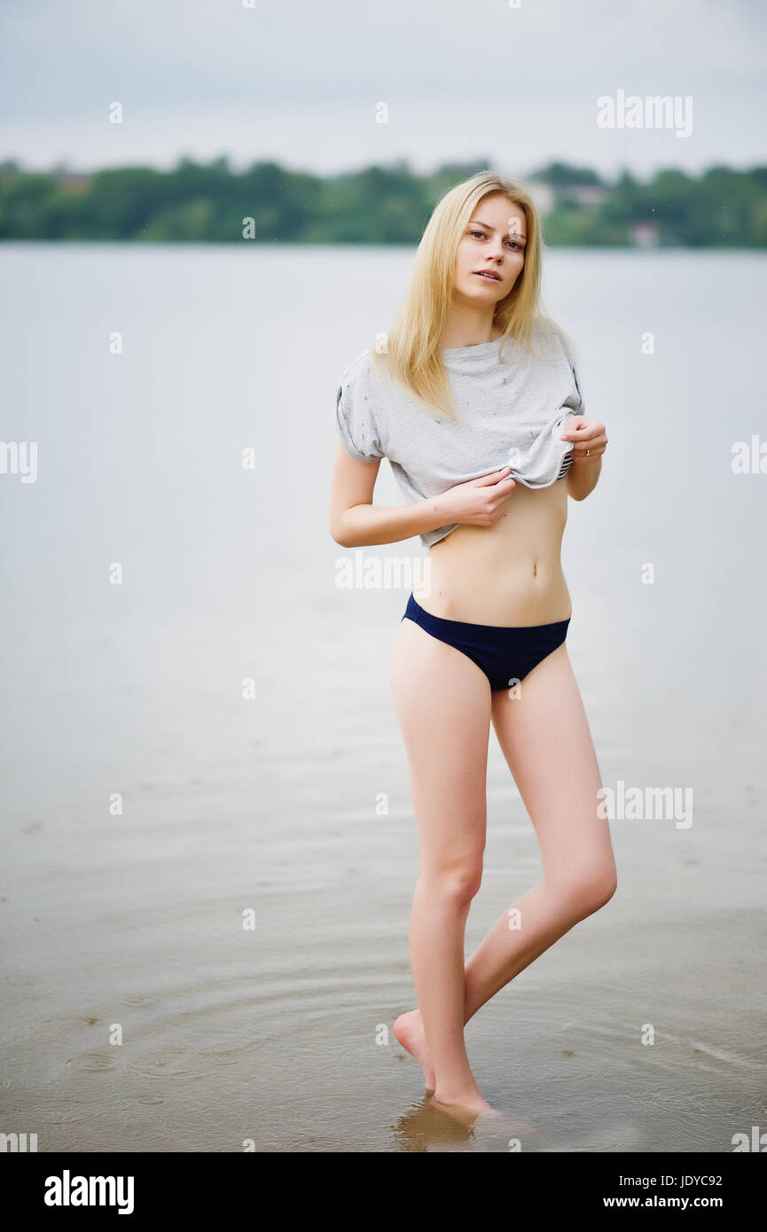 Portrait d'un modèle de grande taille à porter un t-shirt et d'un bikini dans le lac à pied. Banque D'Images