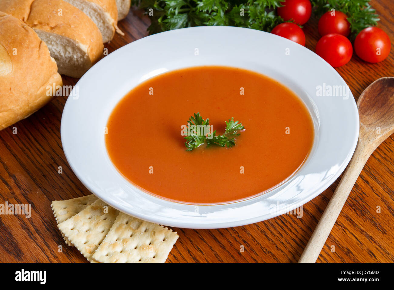 Soupe de tomate dans un bol blanc avec garniture et craquelins à l'arrière-plan Banque D'Images