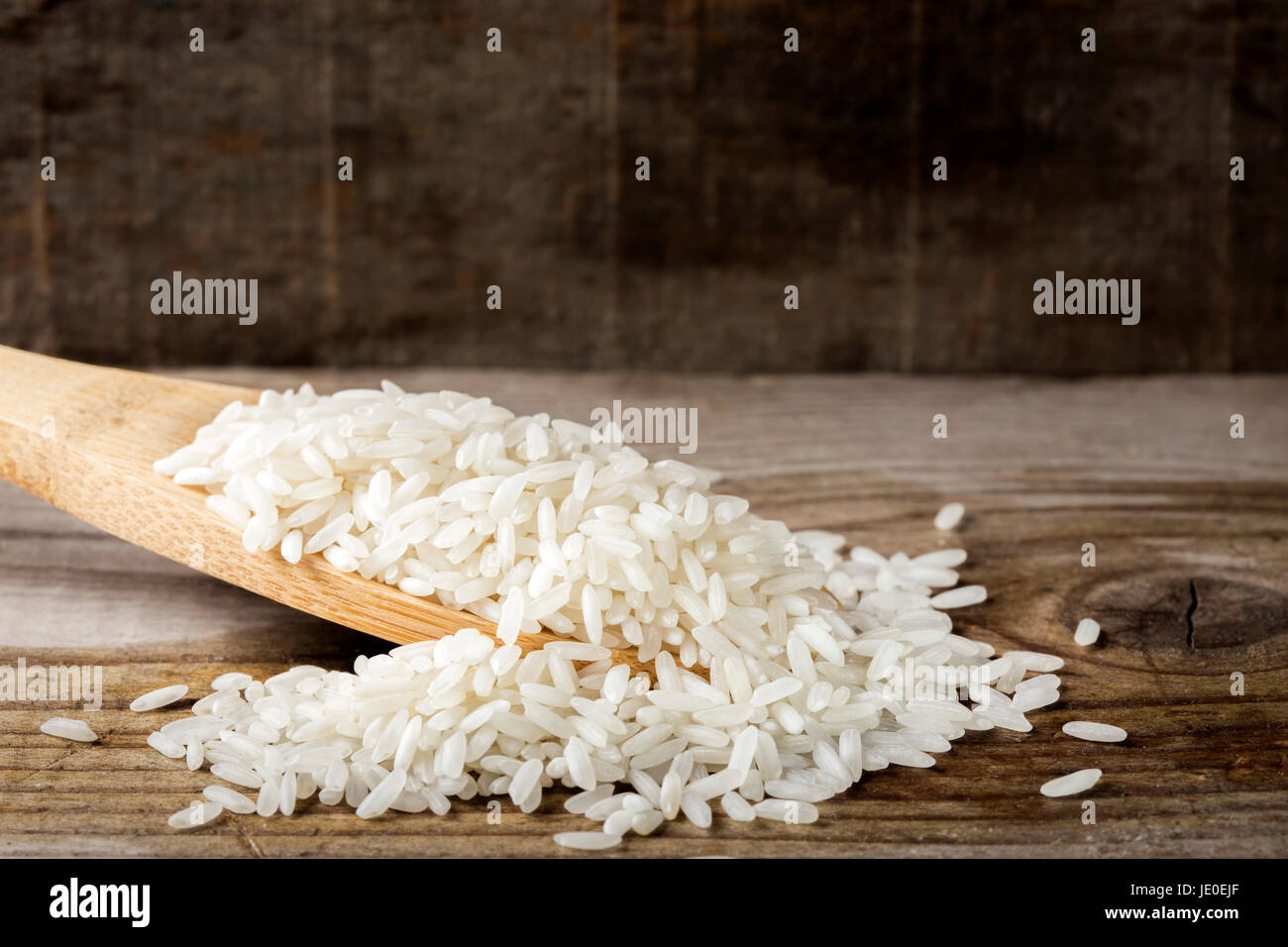 Cuillère en bois rempli de riz sur fond de bois rustique Banque D'Images