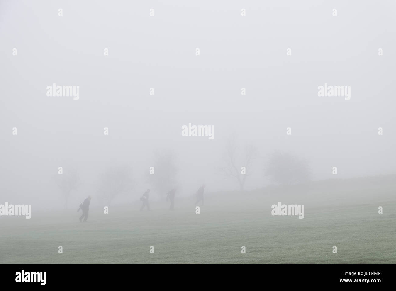 Un groupe de quatre hommes déterminés à jouer au golf dans un épais brouillard Banque D'Images
