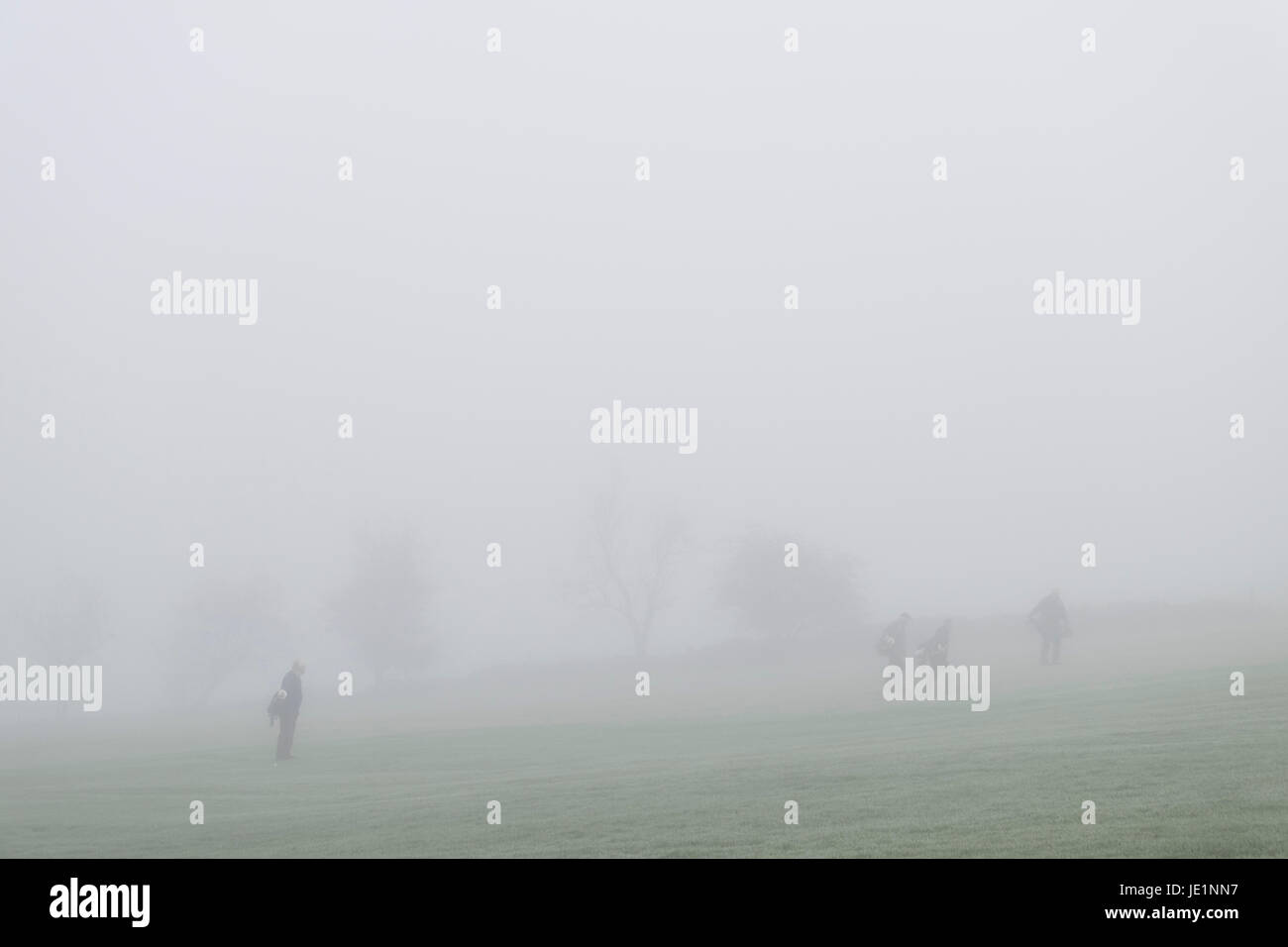Un groupe de quatre hommes déterminés à jouer au golf dans un épais brouillard Banque D'Images