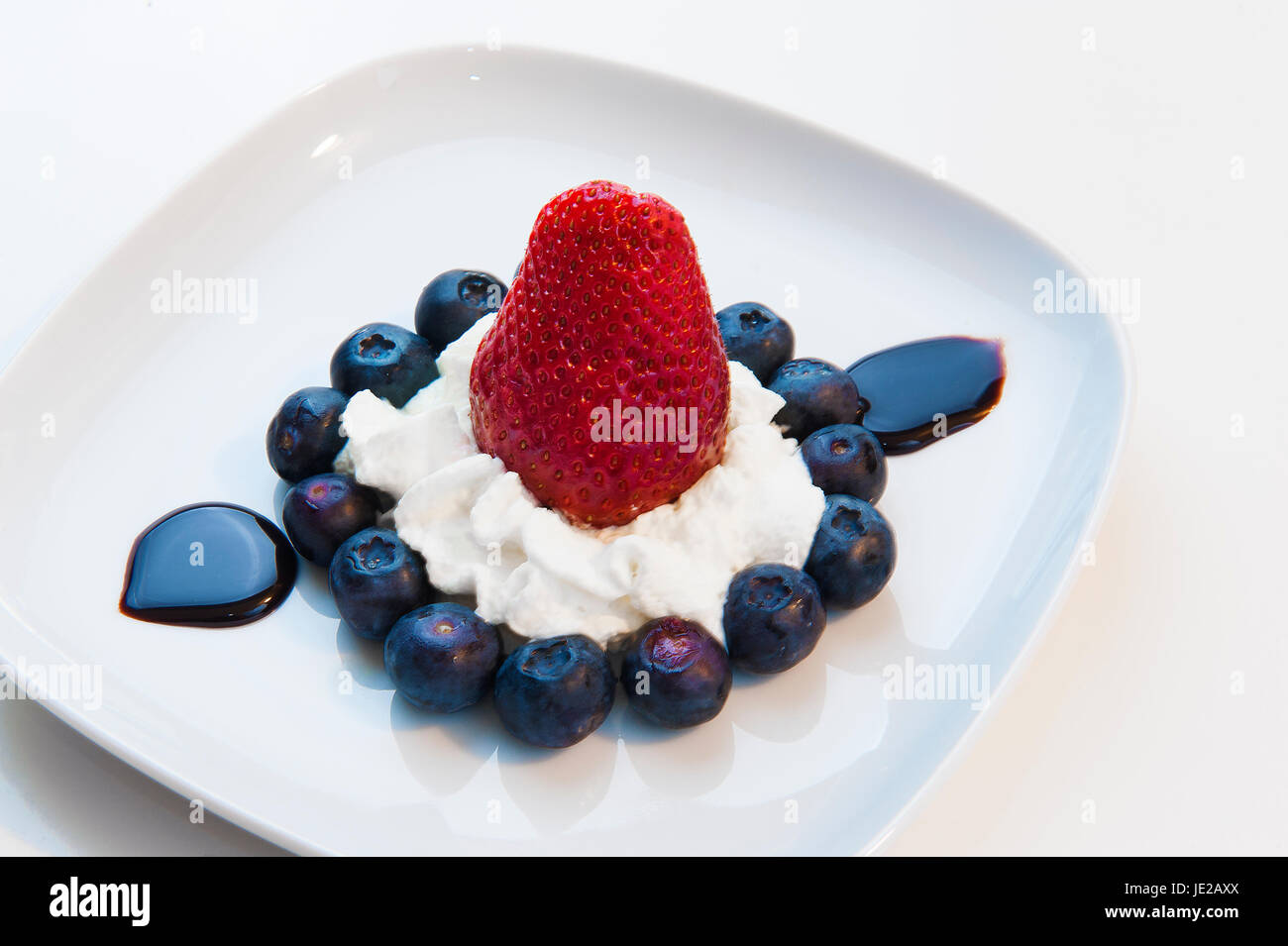 Le Dessert se compose de bleuets, fraises, crème et chocolat liquide Banque D'Images