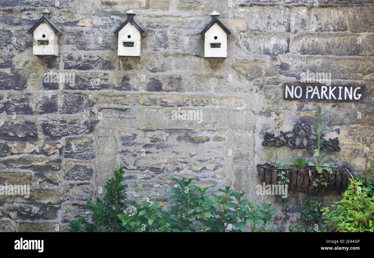 Trois boîtes d'oiseaux en bois et d'un parking pas signer sur mur en pierre Banque D'Images