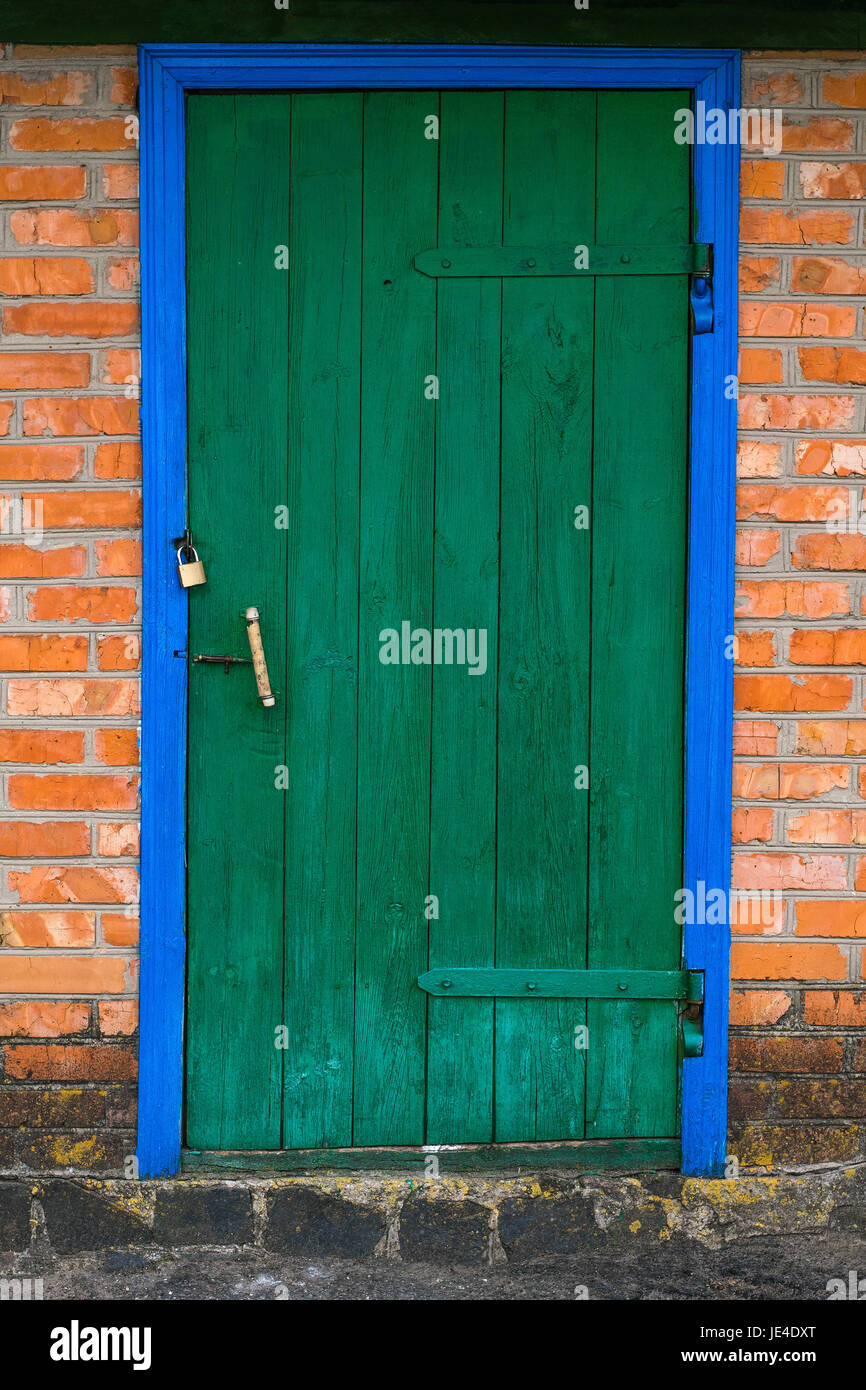 Ancienne grange avec porte en bois de couleur vert et mur de brique Banque D'Images Ancienne grange avec porte en bois de couleur vert et mur de brique Banque D'Images