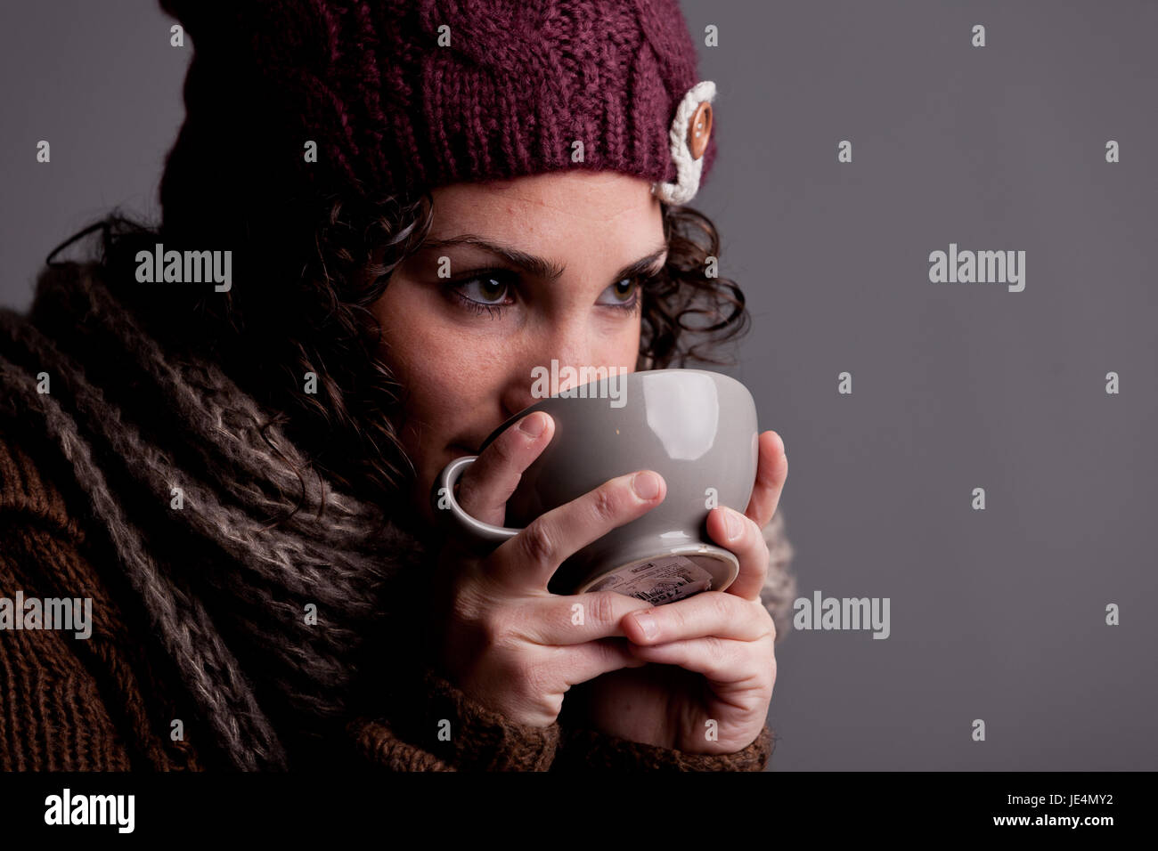 C'est l'hiver et cette fille avec bonnet et écharpe de laine de verre un chocolat  chaud ou du thé chaud et du lait d'une grande tasse et elle est heureuse  Photo Stock -