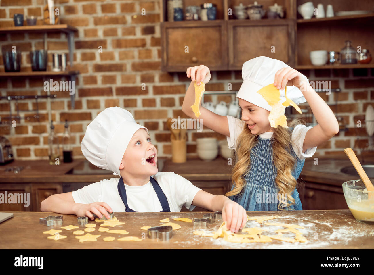 Heureux les enfants jouant avec la pâte en forme de cookies dans la cuisine Banque D'Images