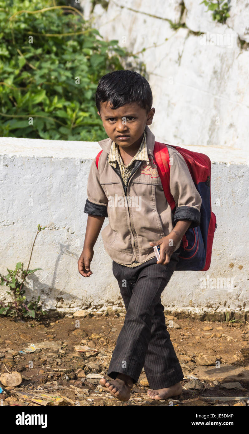 Nilgiri, Inde - le 26 octobre 2013 : un jeune écolier tamoul avec veste beige, pantalon noir et rouge des promenades à dos de son école primaire dans la vill Banque D'Images