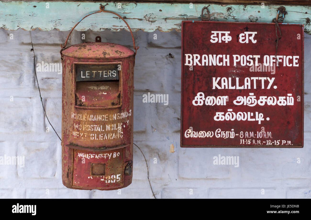 Nilgiri, Inde - le 26 octobre 2013 : Libre de boîte aux lettres rouillée et signe en Kallatty Bureau de poste. L'écriture blanche sur le panneau rouge en tamoul et en anglais. Gr Banque D'Images