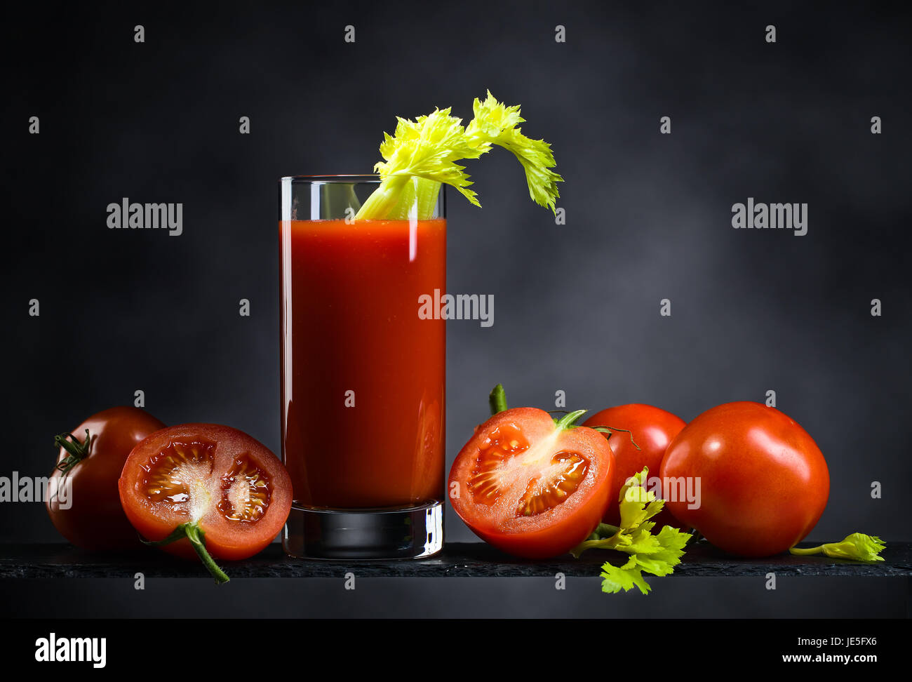 Du jus de tomates ou un cocktail bloody Mary avec des tomates et du céleri sur un fond sombre