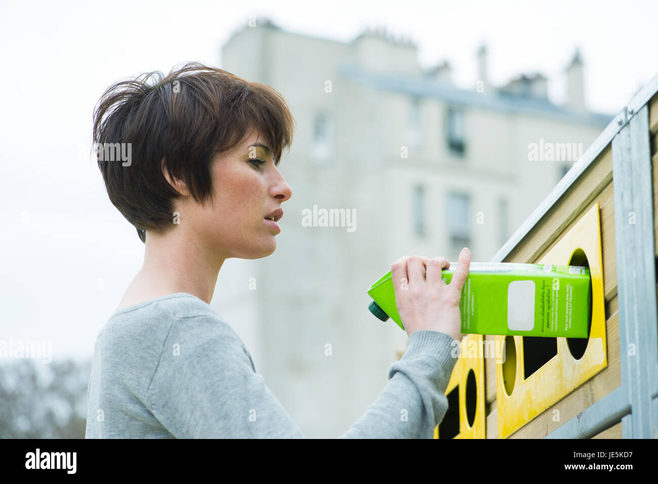 Femme mise en carton recycling bin Banque D'Images