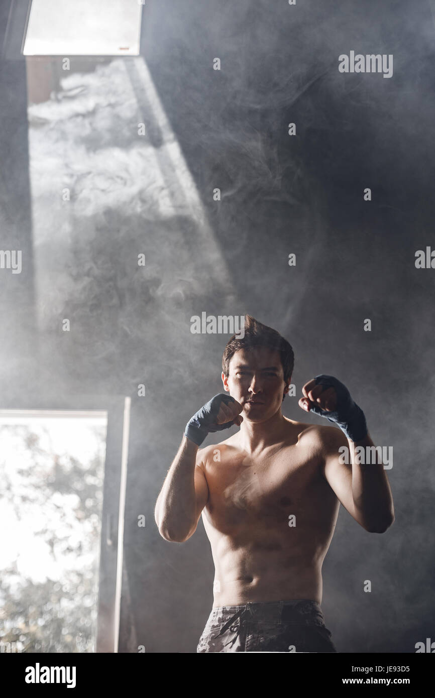 Strong boxer dans les rayons du soleil et de la fumée dans la salle de remise en forme Banque D'Images