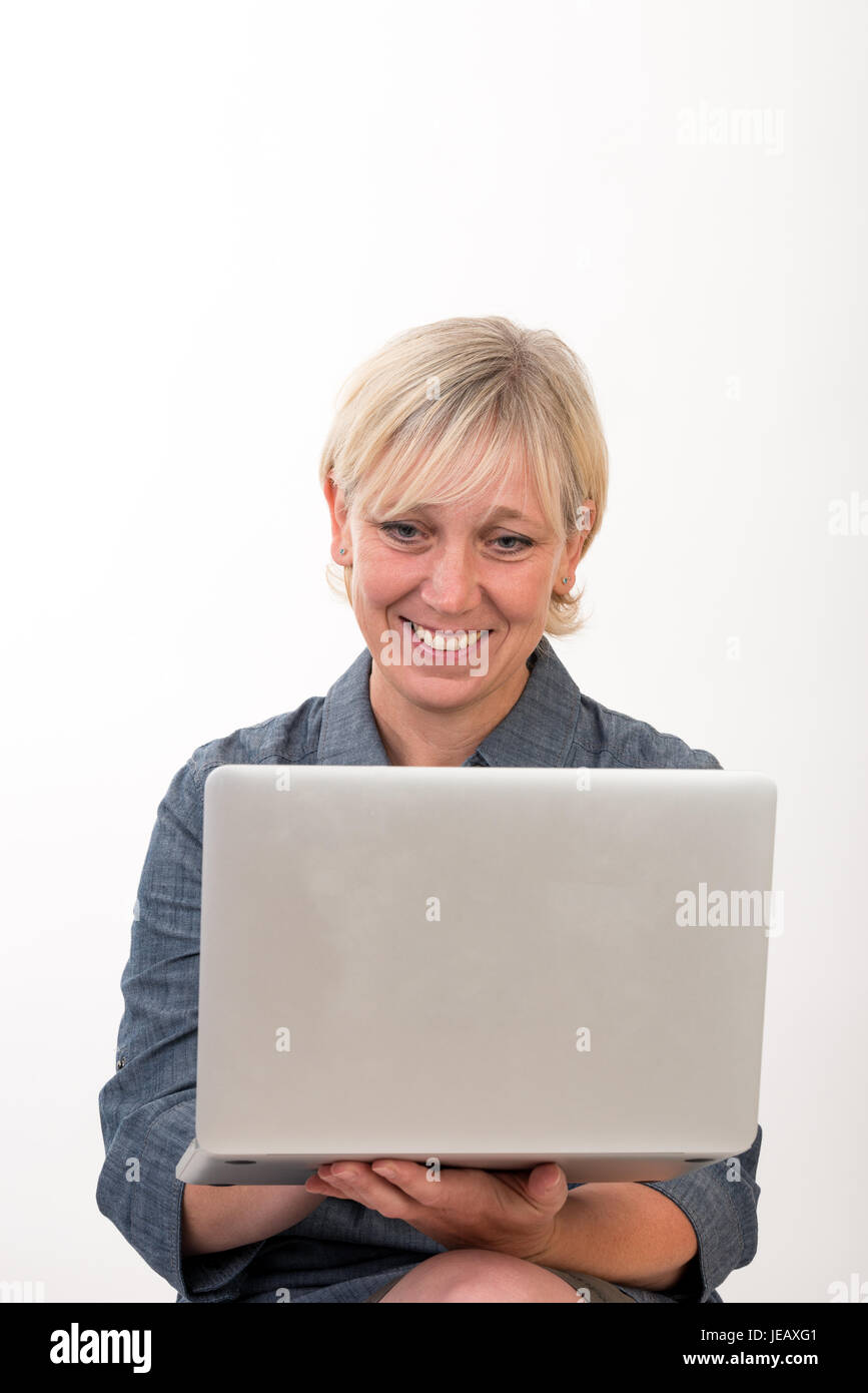 Belle femme d'âge intermédiaire européen travaillant sur un ordinateur portable - studio tourné en face de fond clair Banque D'Images