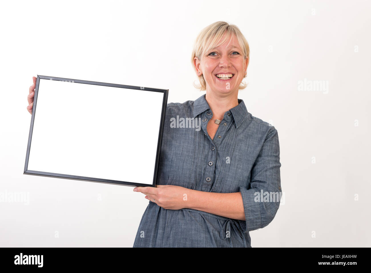 Belle femme d'âge intermédiaire européen dans les affaires dress holding a blank white board - studio shot devant un fond blanc Banque D'Images