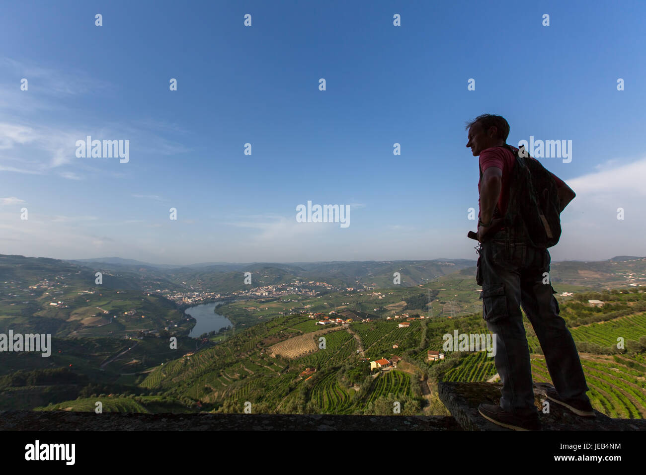 Jeune homme hiker with backpack se détendre au sommet d'une montagne et profiter de la vue sur la vallée du Douro, Portugal. Banque D'Images