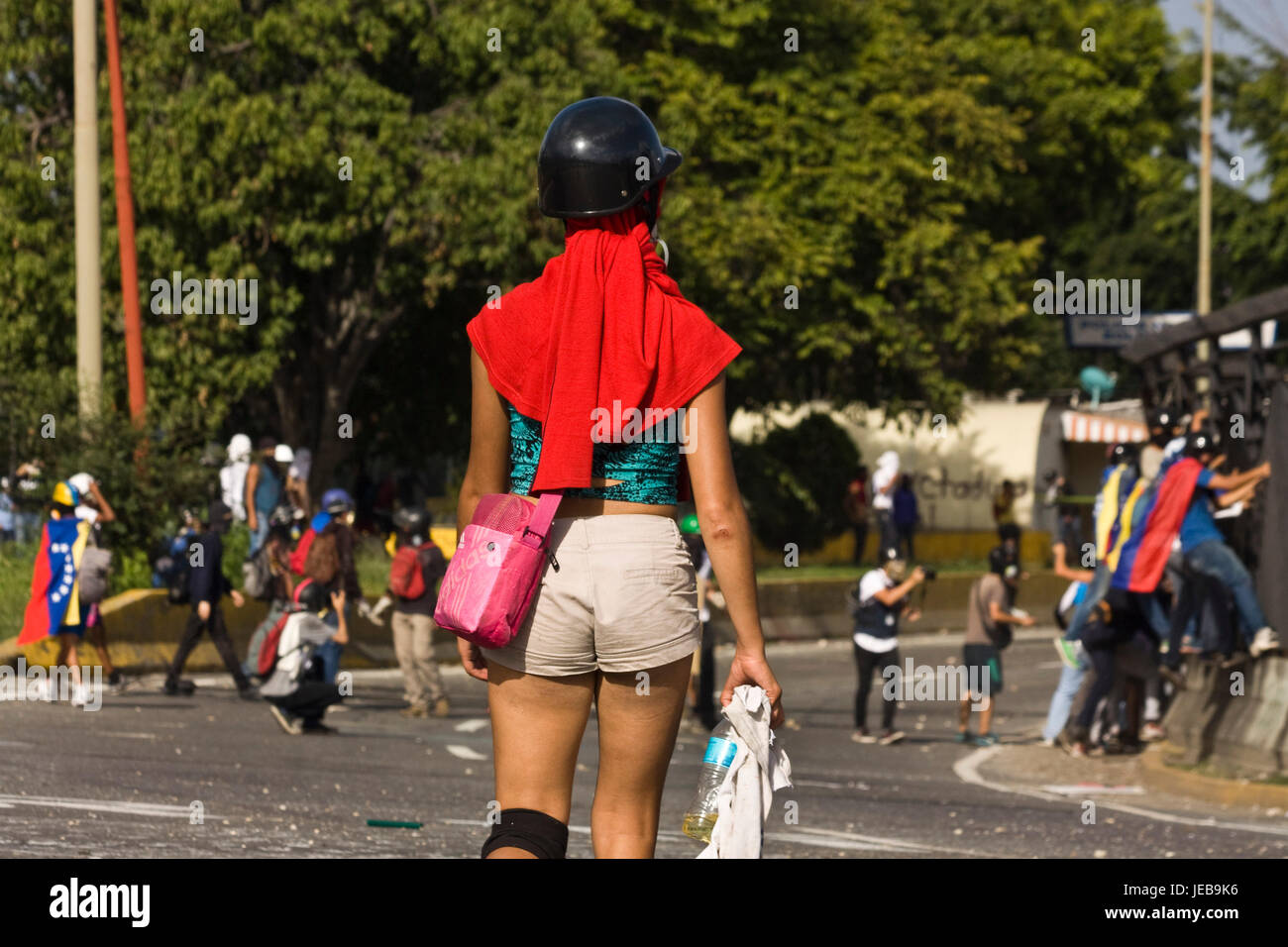 Une jeune fille manifestant observer un groupe de manifestant des affrontements avec les forces de sécurité lors d'une manifestation sur la voie publique. Banque D'Images