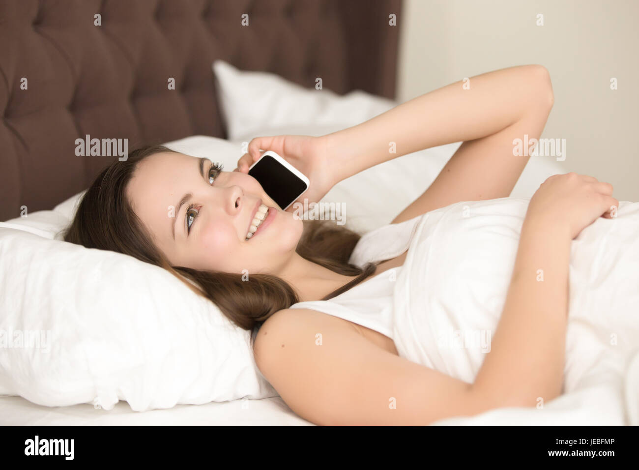 Teen girl in bed parle au téléphone avec petit ami Banque D'Images