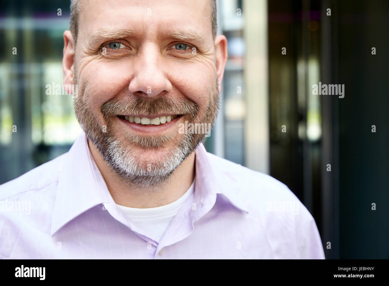 Real man smiling with beard, Close up portrait portrait. Il est debout en face de son bureau. Banque D'Images