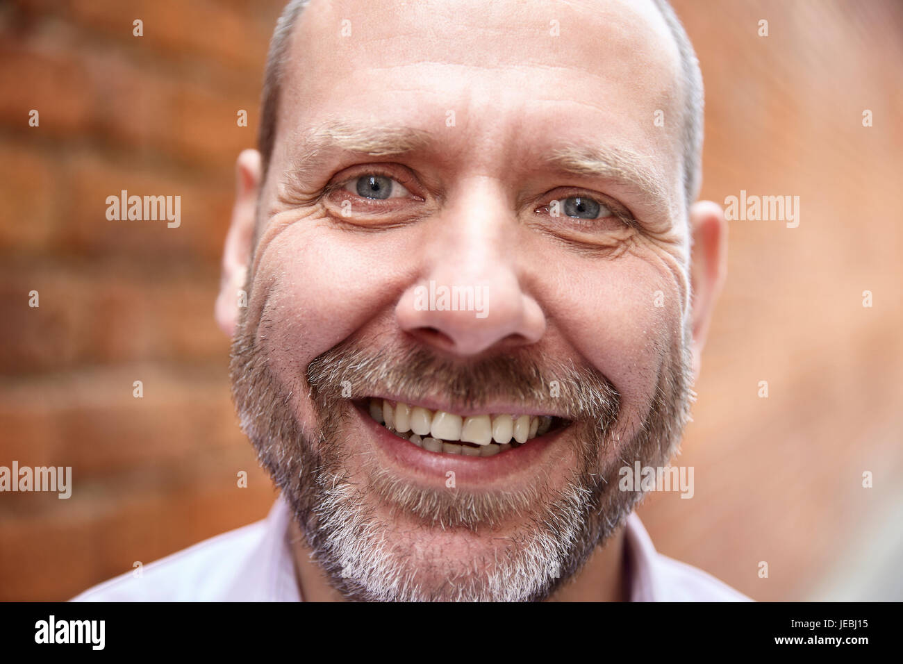 Close-up portrait portrait of smiling mature réel de l'homme contre un mur de briques. Banque D'Images