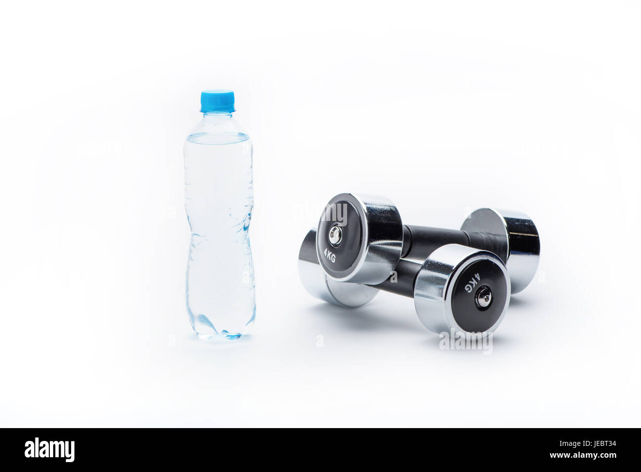 Haltères métalliques et une bouteille avec de l'eau isolé sur blanc. boire de l'eau, de l'équipement sport et vie saine notion Banque D'Images