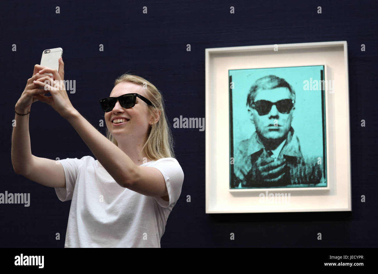 Un visiteur prend un selfie avec 'Self-Portrait' par Andy Warhol (prix estimé de £5 millions - £7 millions) l'une des œuvres en vente à la Contempory Art Evening sale de Sotheby's le 28 juin à Londres. Banque D'Images