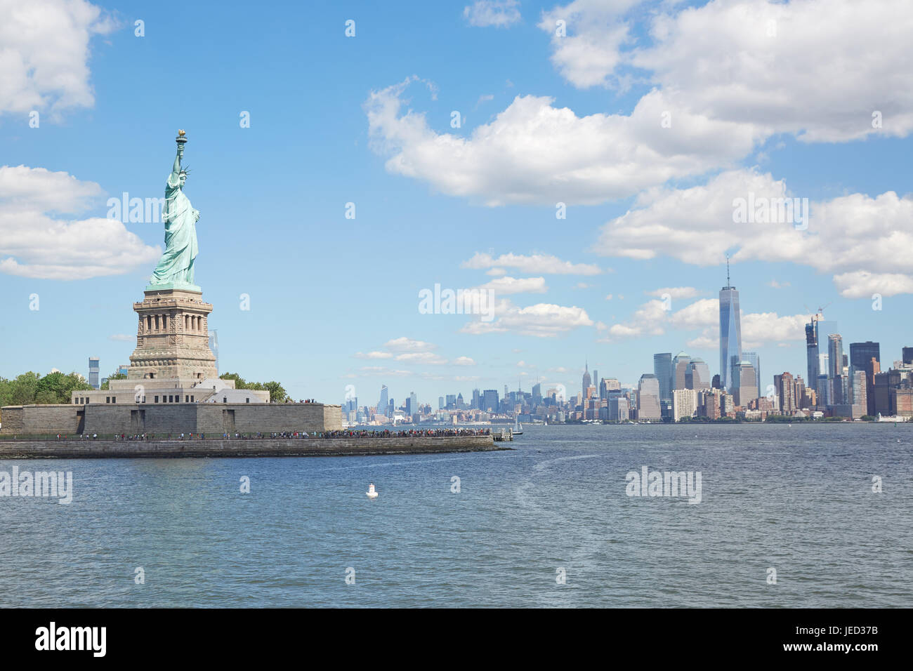 Statue de la liberté et de l'île de New York en une journée ensoleillée, des nuages blancs Banque D'Images