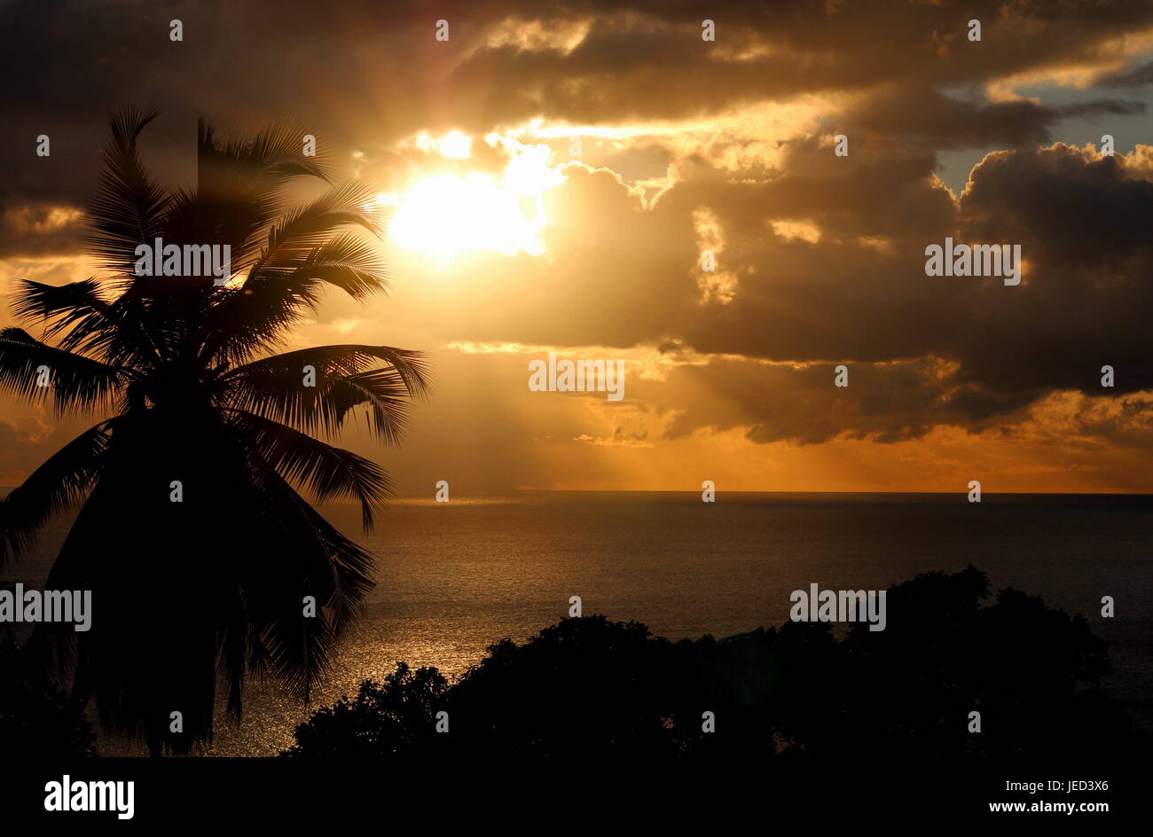 Coucher du soleil éclate à travers les nuages sur l'île de Silhouette Banque D'Images