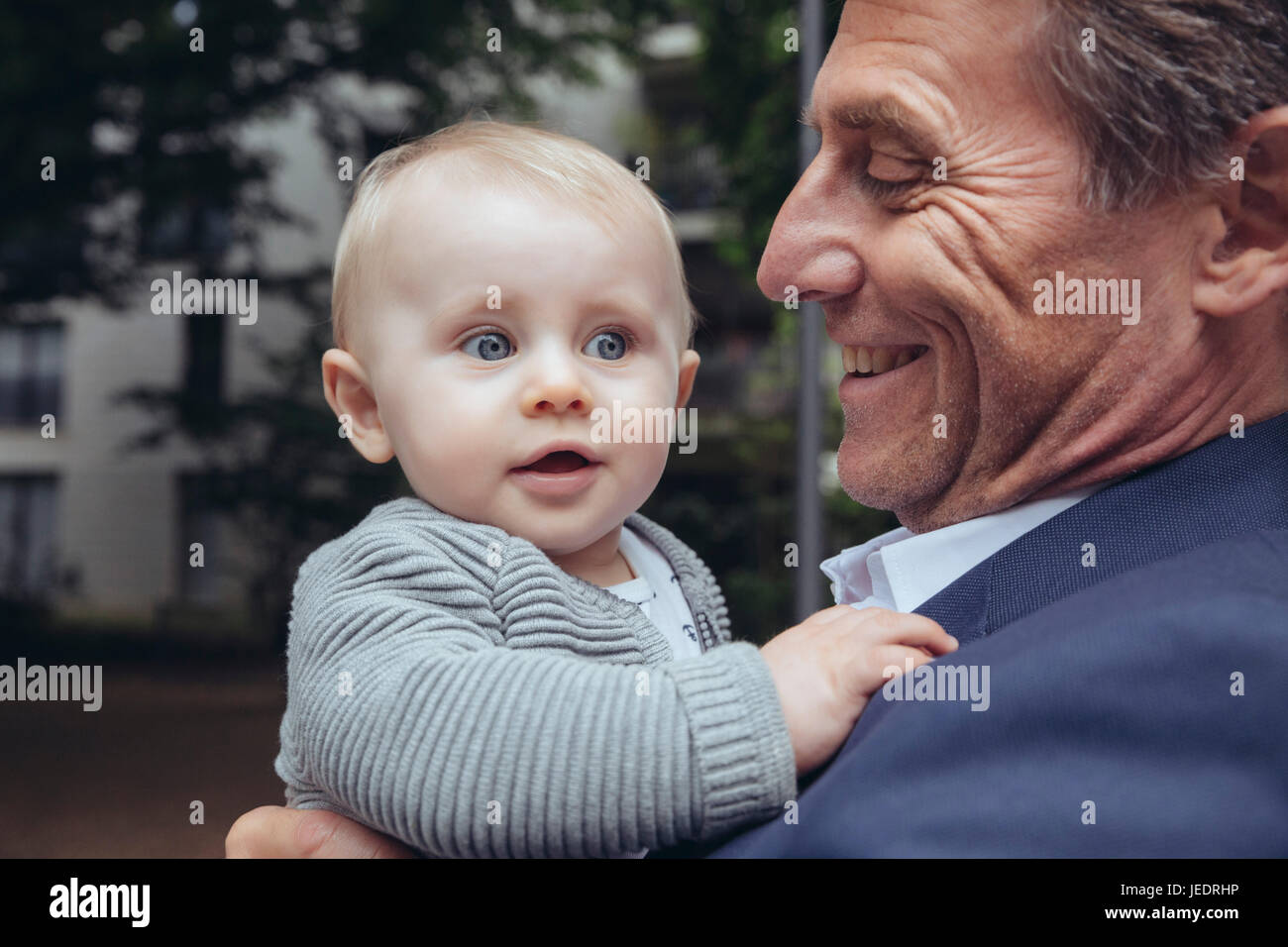 Mature businessman holding baby boy outdoors Banque D'Images