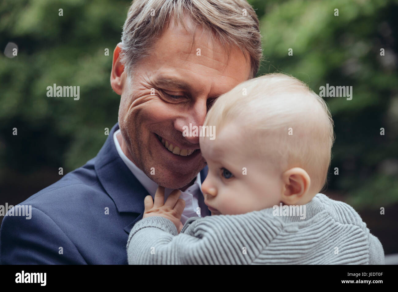 Mature businessman holding baby boy outdoors Banque D'Images