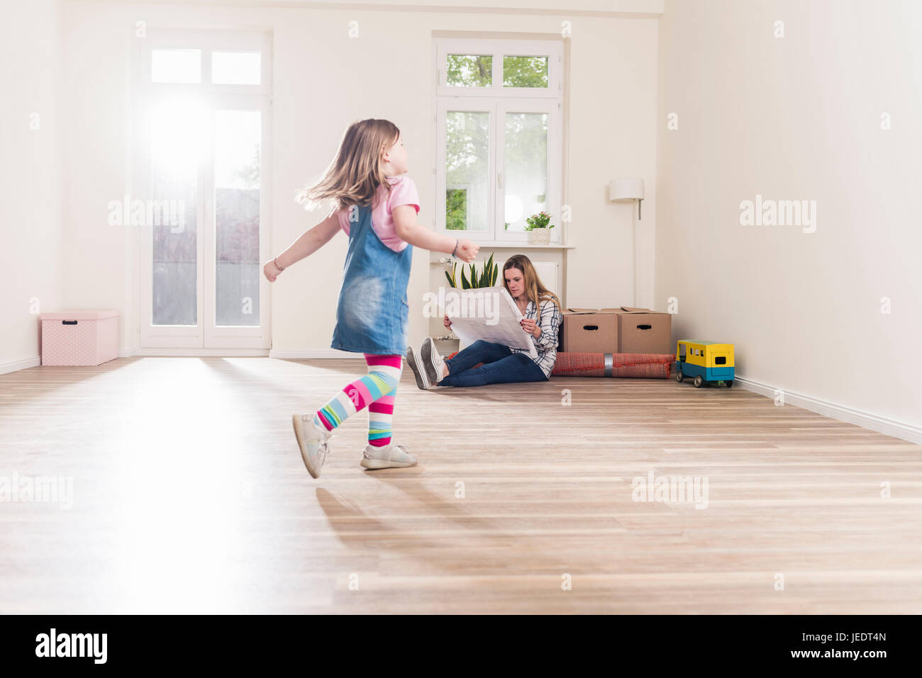 Happy girl running in appartement vide avec plan de lecture de la mère Banque D'Images