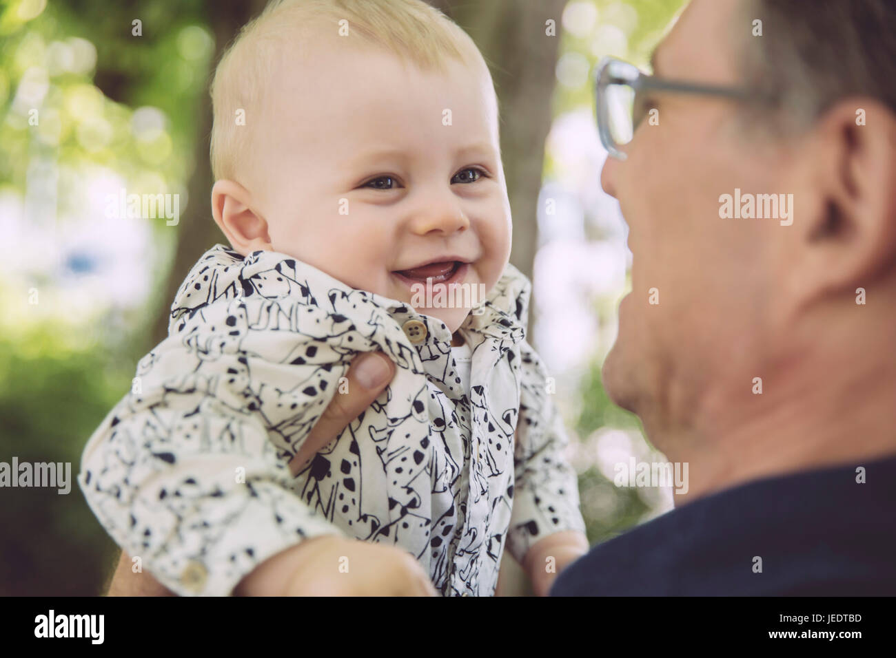 Père holding up happy baby boy outdoors Banque D'Images