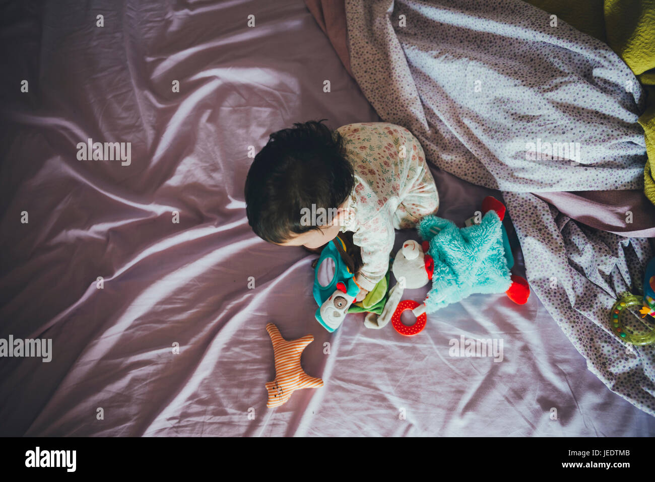 Petite fille jouant avec des jouets dans le lit de partent Banque D'Images