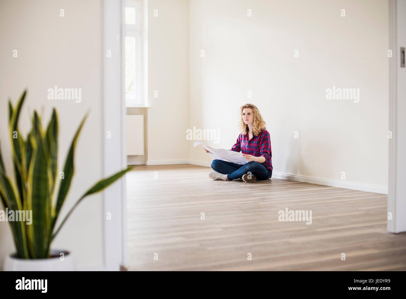 Jeune femme à new home sitting on floor avec plan Banque D'Images