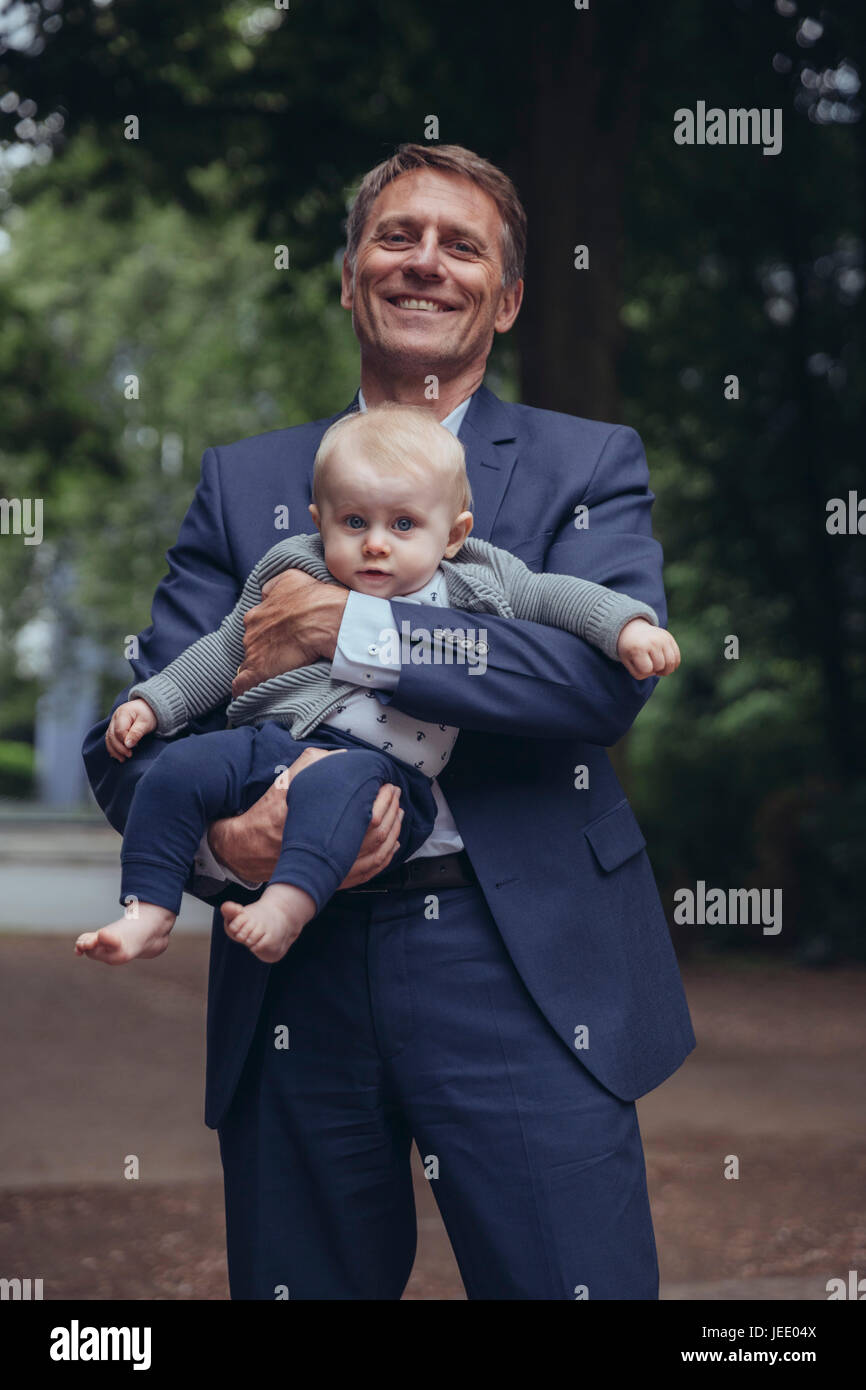 Portrait of smiling senior woman holding baby boy outdoors Banque D'Images
