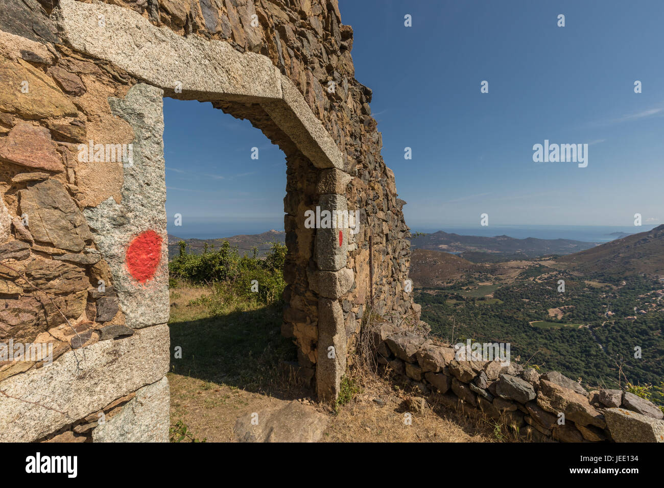 L'entrée en pierre à 'La maison du bandit', le bandit's house, au-dessus du village de Feliceto en Balagne de Corse avec la Vallée du Regino et Banque D'Images