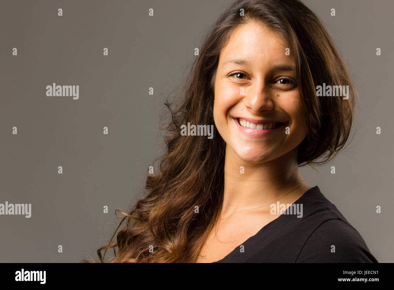 Young mixed race woman wearing a black t-shirt et jeans est pleinement tout en vue de face smiling at viewer Banque D'Images