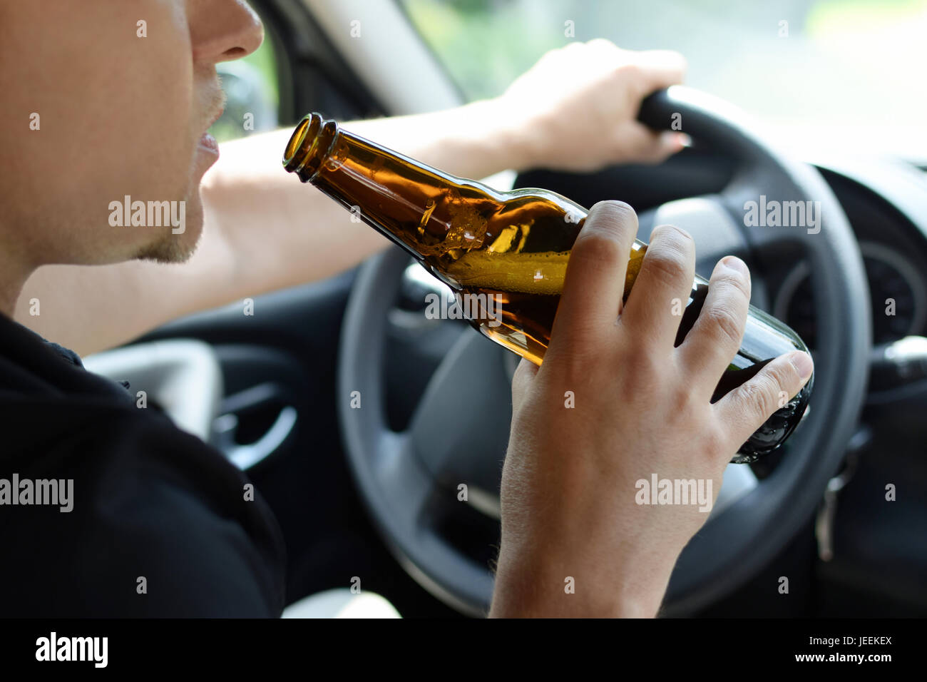 Le concept de l'alcool au volant le crime - gros plan du jeune homme de  mains avec volant et bouteille de bière Photo Stock - Alamy
