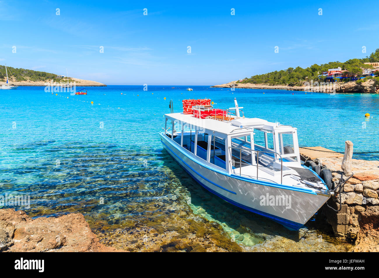 Couleur blanc et bleu pour les touristes en bateau ferry amarre en baie Cala Portinatx, Ibiza island, Espagne Banque D'Images
