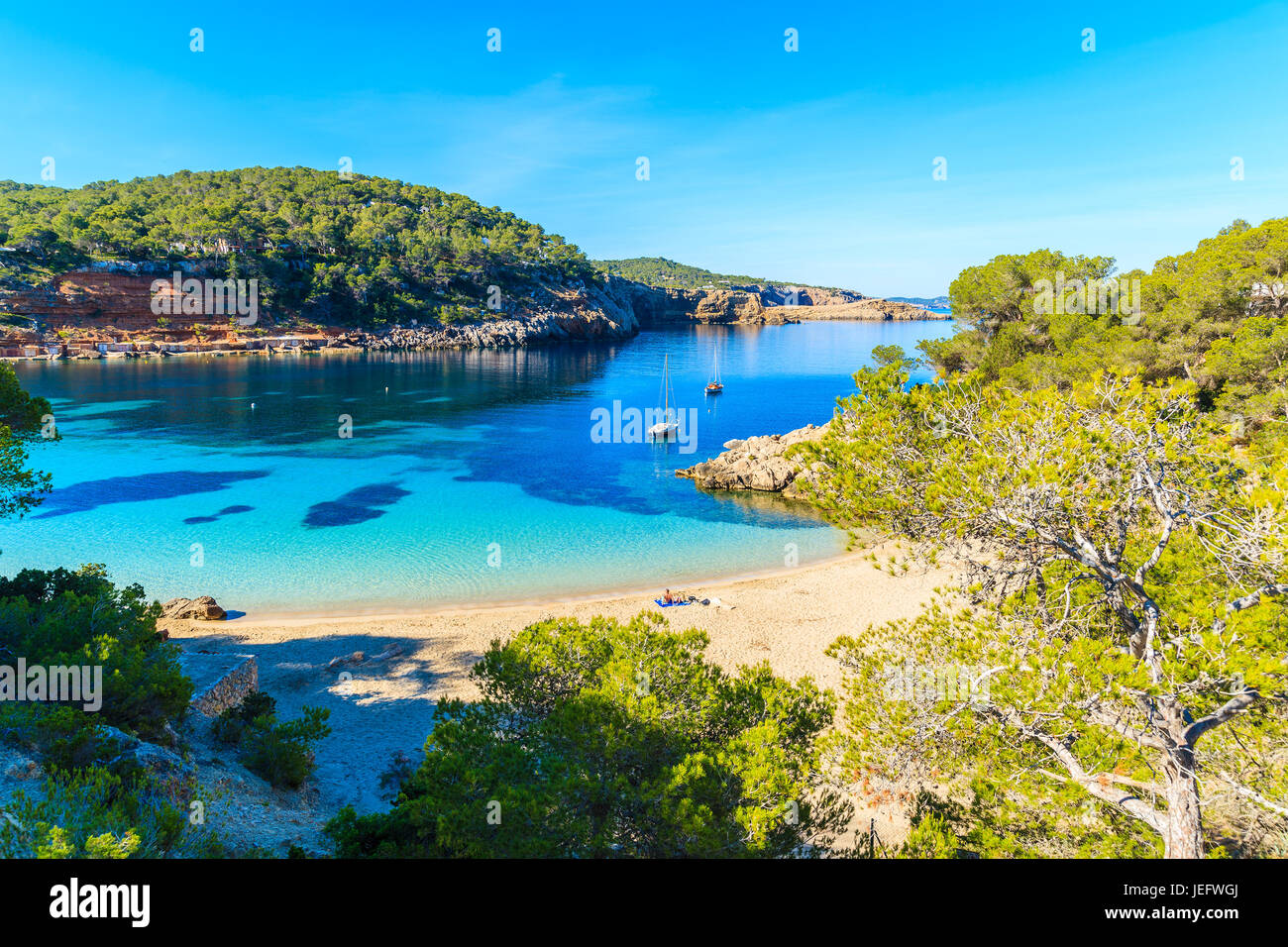 Couple de personnes non identifiée de bronzer sur une belle plage de Cala Salada, célèbre pour ses eaux cristallines de la mer d'azur, l'eau de l'île d'Ibiza, Espagne Banque D'Images