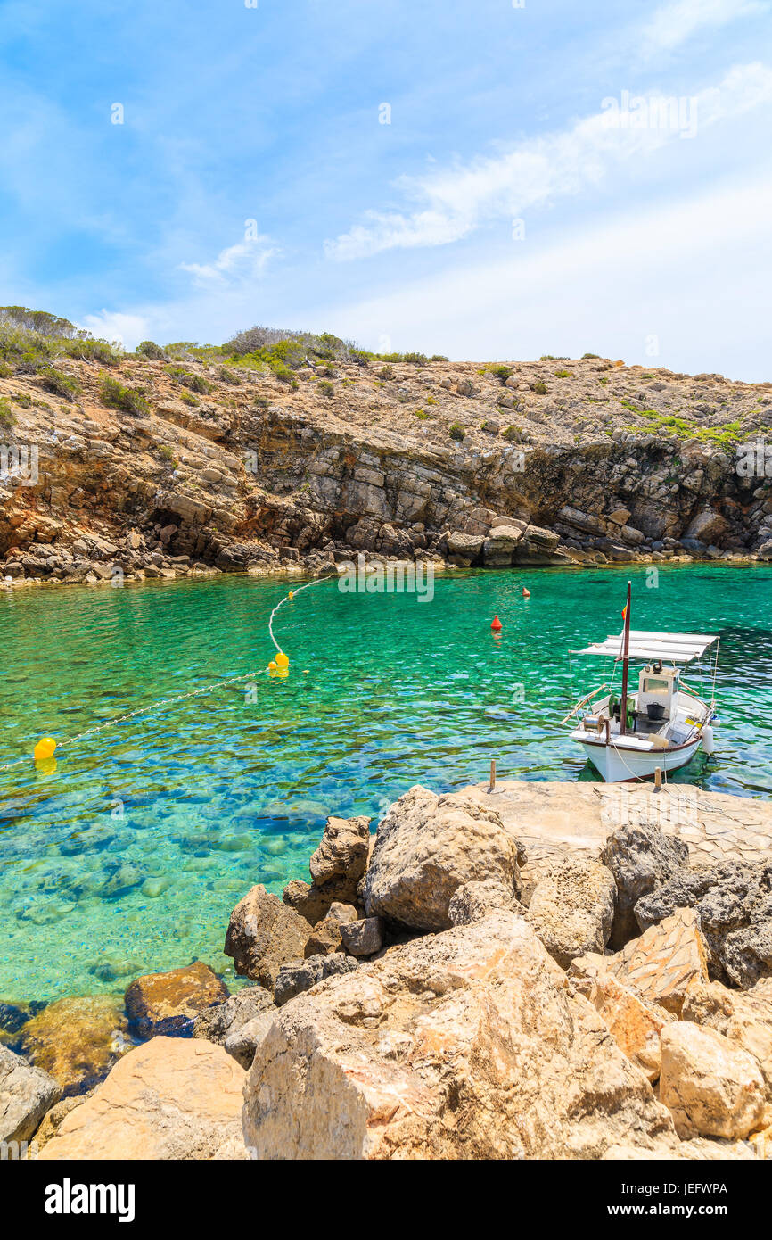 Bateau de pêche typique blanc magnifique mouillage dans la baie de Cala Carbo avec de l'eau de mer vert émeraude, l'île d'Ibiza, Espagne Banque D'Images