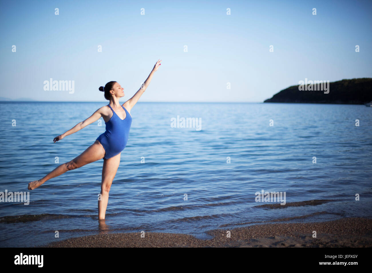 Jeune femme enceinte dans la méditation de yoga on beach Banque D'Images