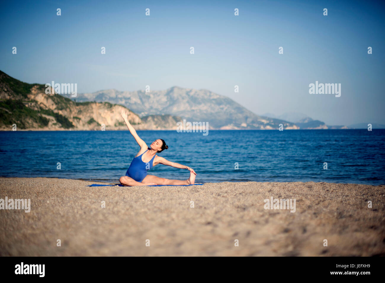 Jeune femme enceinte dans la méditation de yoga on beach Banque D'Images