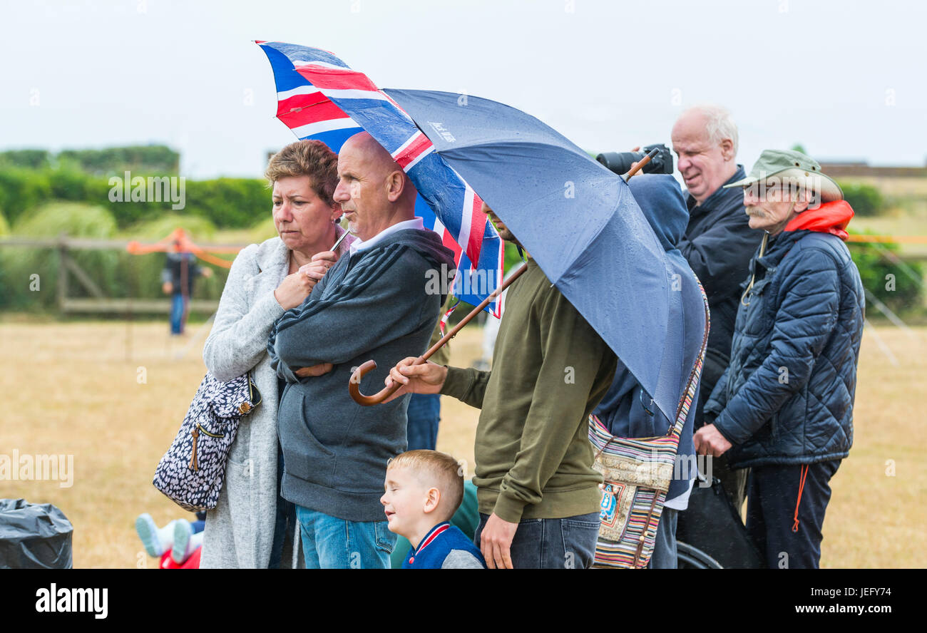 Pluie, des parasols. Groupe de personnes debout à regarder un événement sous la pluie, des parasols. Holding umbrella sous la pluie. Banque D'Images