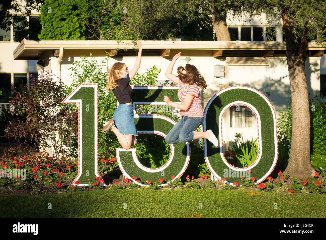 Deux amis des cinq en face d'un Canada signe 150 commémoration de l'anniversaire de 150 ans. L'Assemblée législative du sud, Edmonton, Alberta, Canada. Banque D'Images