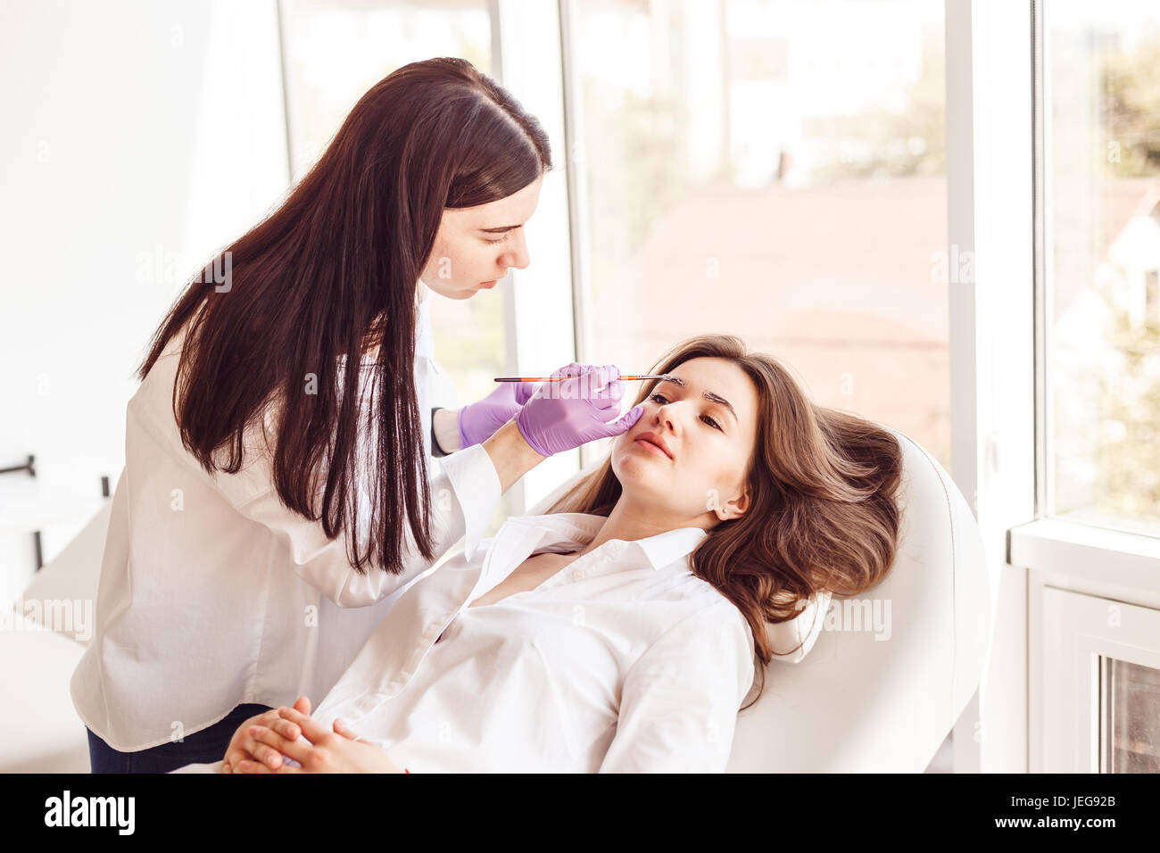 La clientèle féminine est allongé sur une table pendant blanc et correction de style sourcil. Banque D'Images