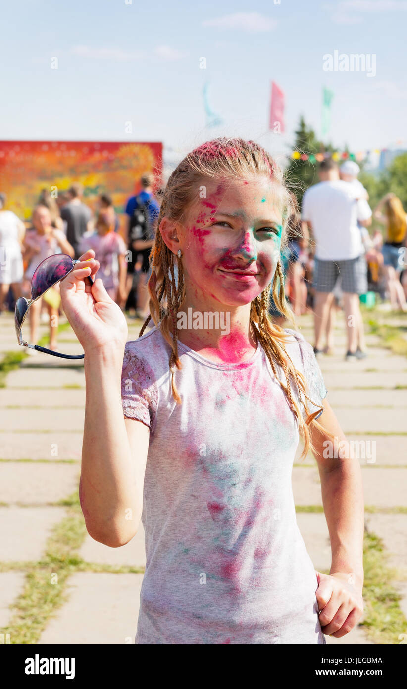 Jeune fille joyeuse arrosée de peinture sèche au festival de peinture Banque D'Images