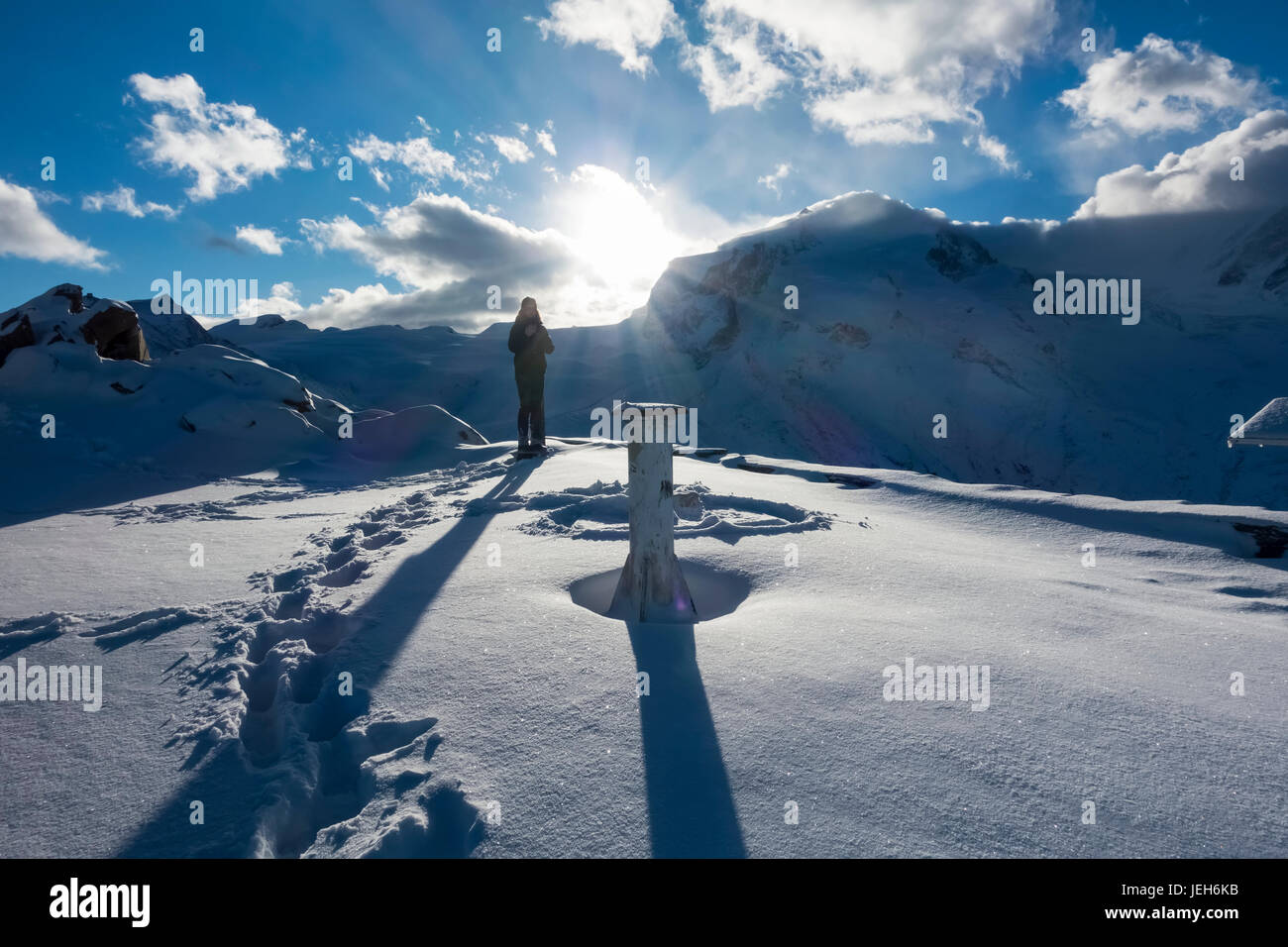 Une femme se tient dans la neige au lever du soleil sur le sommet du Gornergrat, Monte Rosa, Alpes Pennines, Zermatt, Valais, Suisse Banque D'Images